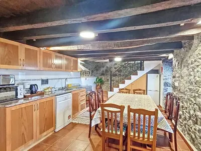 a kitchen with a table and chairs and a kitchen with a stone wall at Holiday Home Haus Seixal by Interhome in Seixal