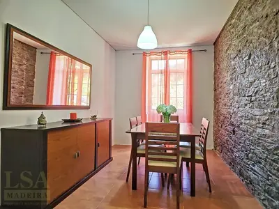 a dining room with a table and a stone wall at Holiday Home Quinta do Serrado 2 by Interhome in Ribeira da Janela
