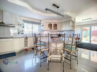 a kitchen with white cabinets and a table and chairs at Holiday Home PEARLS BEACH VILLA by Interhome in Porto Moniz