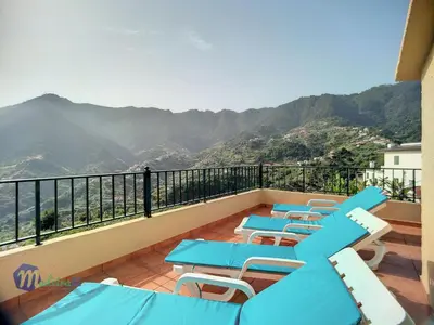 a balcony with blue tables and chairs and mountains at Holiday Home Casa do Romaninho by Interhome in Porto da Cruz