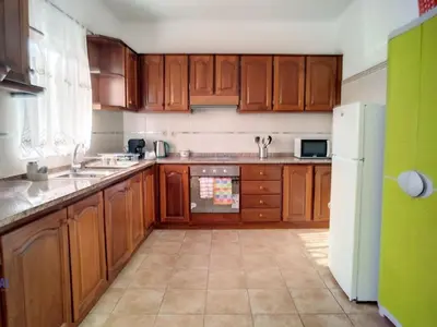 a kitchen with wooden cabinets and a white refrigerator at Holiday Home Casa do Romaninho by Interhome in Porto da Cruz