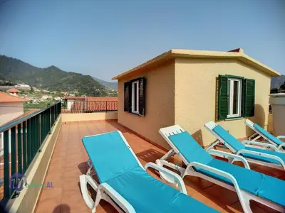 a balcony with blue lounge chairs and a house at Holiday Home Casa do Romaninho by Interhome in Porto da Cruz