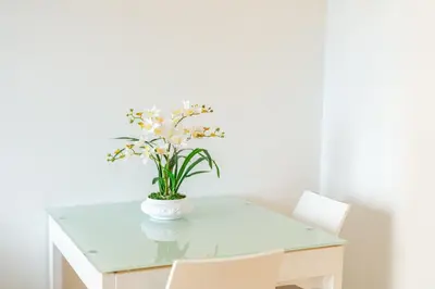 a white table with a vase of flowers on it at Madeira Holidays Studio by Amazing Madeira in Funchal