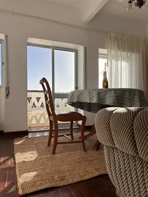 a dining room with a table and a chair and a couch at Casinha Menta in Carrapateira