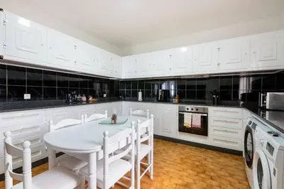 a kitchen with white cabinets and a table and chairs at Villa Jardim by GALMI in São Vicente