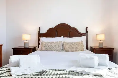 a bedroom with a white bed with two lamps at Villa Jardim by GALMI in São Vicente