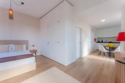 a white bedroom with a bed and a kitchen at Angie's House in Funchal