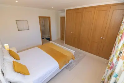 a bedroom with a bed and wooden cabinets at Casa Magnólia in Luz