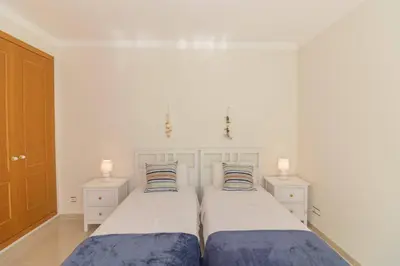 two beds in a white bedroom with two lamps at Casa Magnólia in Luz
