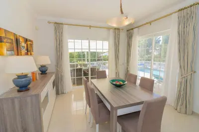 a dining room with a table and chairs and a window at Casa Magnólia in Luz