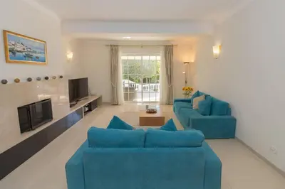 a living room with two blue couches and a tv at Casa Magnólia in Luz