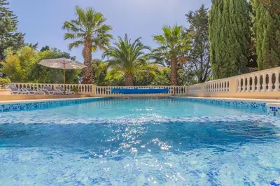 a swimming pool with a fence and palm trees at Casa Magnólia in Luz