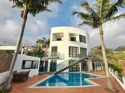 a house with a swimming pool and palm trees at Blue Horizon House in Funchal