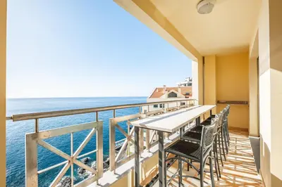 a balcony with a table and chairs overlooking the ocean at Cliff View Apartment - By Wehost in Funchal