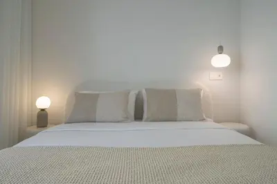 a bedroom with a white bed with pillows and two lights at With patio in Funchal city centre - AL'gria I in Funchal