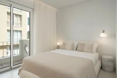 a white bedroom with a large bed and a window at With patio in Funchal city centre - AL'gria I in Funchal