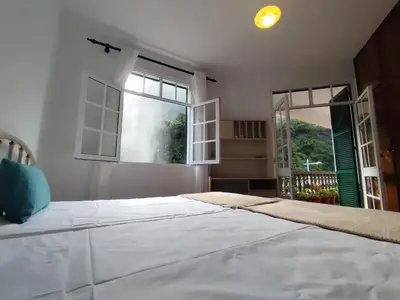 a bedroom with a large white bed and two windows at Narciso's House in São Vicente