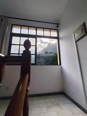 a room with a large window with a mountain view at Narciso's House in São Vicente