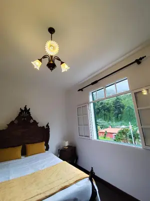 a bedroom with a bed with a window and a chandelier at Narciso's House in São Vicente