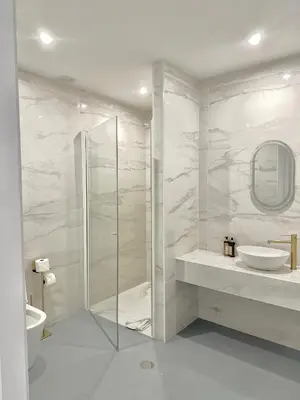 a white bathroom with a shower and a sink at Espada Preta Apartments in Câmara de Lobos