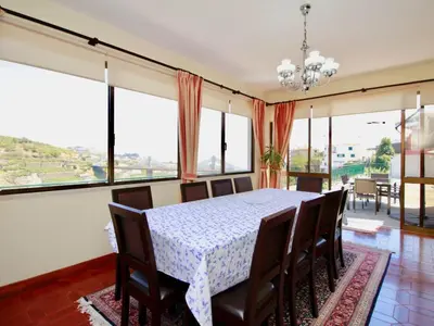 a dining room with a table and chairs and large windows at Holiday Home Villa Lapa in Câmara de Lobos by Interhome in Câmara de Lobos