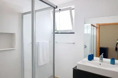 a bathroom with a glass shower and a sink at Penthouse Montanha-Mar in Machico