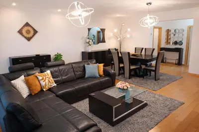 a living room with a leather couch and a dining room at Penthouse Montanha-Mar in Machico