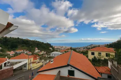 a view of a town with orange roofs and the ocean at Cozy Studio & Patio in Funchal in Funchal
