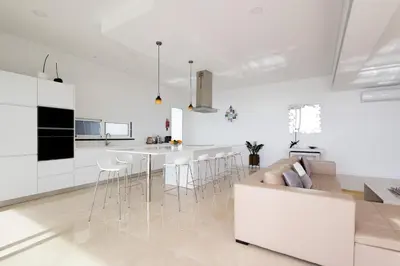 a white kitchen and living room with a couch and chairs at Bela Vista - pool in Arco da Calheta