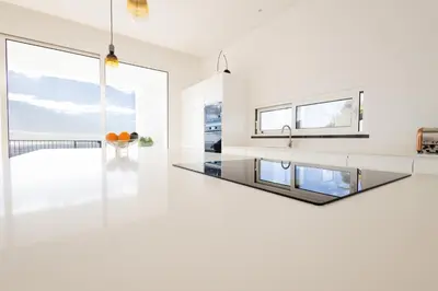 a kitchen with white countertops and large windows at Bela Vista - pool in Arco da Calheta