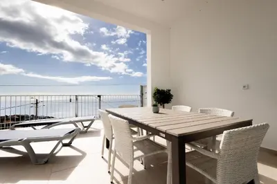 a table and chairs on a balcony with a view of the ocean at Bela Vista - pool in Arco da Calheta