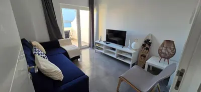 a living room with a blue couch and a tv at Sagres Escape Near Mareta Beach in Sagres