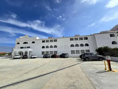 a large white building with cars parked in a parking lot at Sagres Escape Near Mareta Beach in Sagres