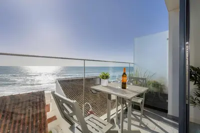 a table and chairs on a balcony with the ocean at NEW Salema Seaview in Salema