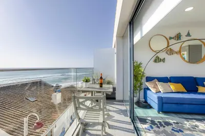 a balcony with a blue couch and a view of the ocean at NEW Salema Seaview in Salema