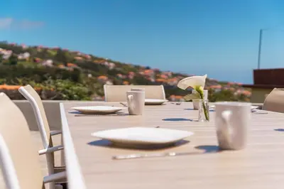 a long wooden table with plates and flowers on it at GuestReady - Escape with Ocean and Mountain Views in Calheta