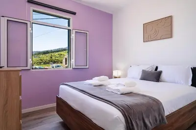 a bedroom with a large bed with purple walls and a window at GuestReady - Escape with Ocean and Mountain Views in Calheta