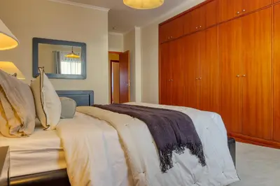 a bedroom with a large bed with a wooden cabinet at Emma's Place, a Home in Madeira in Funchal
