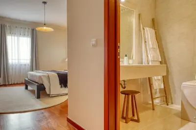 a bedroom with a bed and a bathroom with a sink at Emma's Place, a Home in Madeira in Funchal