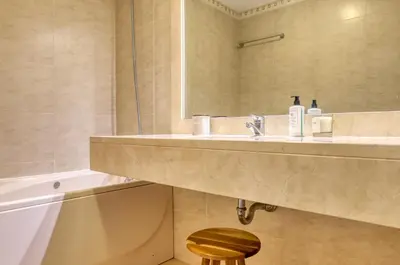 a bathroom with a sink and a mirror and a stool at Emma's Place, a Home in Madeira in Funchal