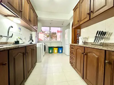 a large kitchen with wooden cabinets and a tile floor at Santa Luzia pokoje in Funchal