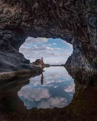 a cave with a reflection of the sky in the water at Casa Alba - Sunrise and Sea View Balcony - Apt 1 in Seixal