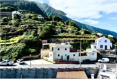 a house on a hill with cars parked in a parking lot at Casa Alba - Sunrise and Sea View Balcony - Apt 1 in Seixal