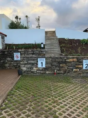 a stone wall with signs in front of a building at Sunset Eco Shelter 1 in Ponta do Pargo