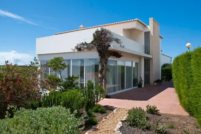 a white house with glass windows and bushes at Casa de Praia na Carrapateira in Bordeira