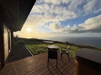 a table and two chairs on a deck with a view of the ocean at Sunset Eco Shelter 3 in Ponta do Pargo