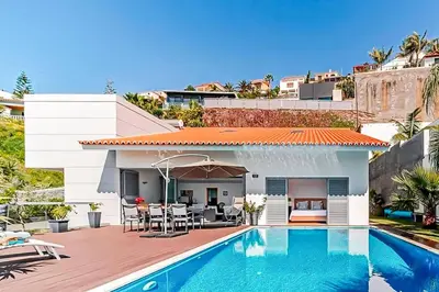 a villa with a swimming pool in front of a house at Villa Sol e Mar Dio by Villa Plus in Caniço