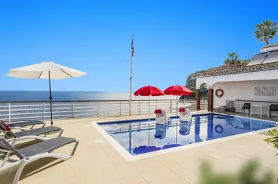 a swimming pool with chairs and umbrellas and the ocean at Villa Sea Shore Dio by Villa Plus in Gaula