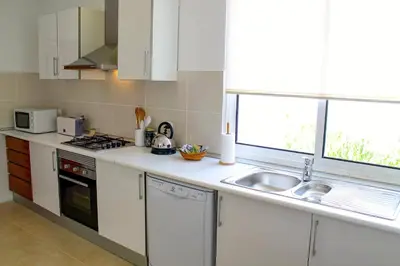 a kitchen with white cabinets and a sink and a window at Villa Casa Amelia Dio by Villa Plus in Caniço