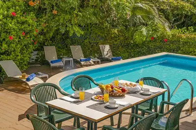 a table with a bowl of fruit next to a swimming pool at Villa Casa Amelia Dio by Villa Plus in Caniço